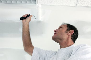 Painter using roller on ceiling clipart