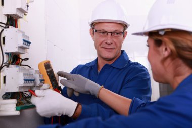 Electricians working on an electric meter clipart