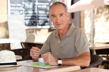 Older man drinking an expresso outside a cafe clipart