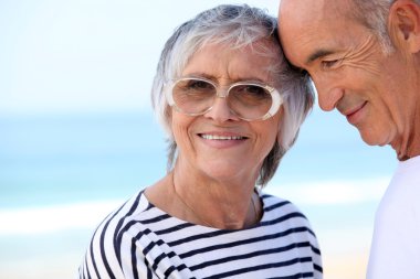 Elderly couple at the beach together clipart