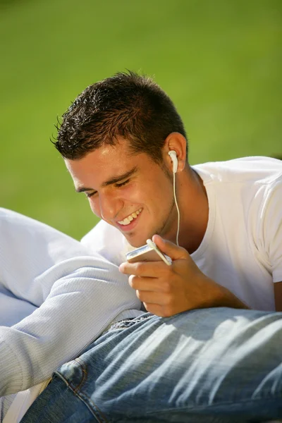 Couple laying in park listening to music — Stock Photo, Image