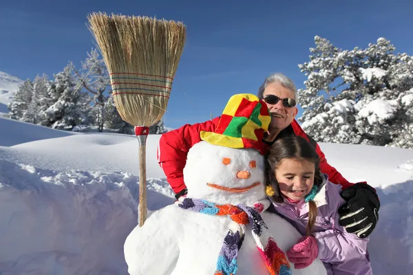 Девочка и дедушка со своим снеговиком — стоковое фото