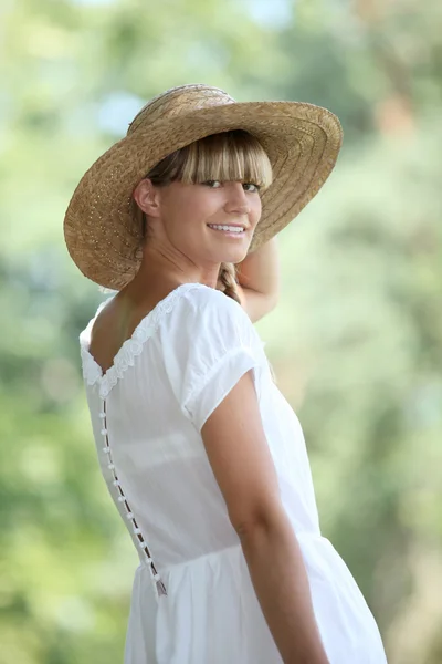 Mujer rubia de 30 años con un vestido blanco y un sombrero de paja caminando —  Fotos de Stock
