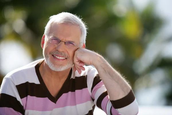 Счастливый пожилой человек, сидящий на солнышке — стоковое фото