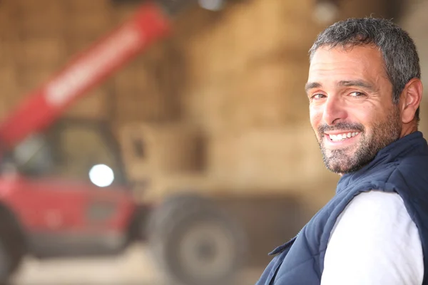 Agricoltore in piedi di fronte a cauzioni di fieno — Foto Stock