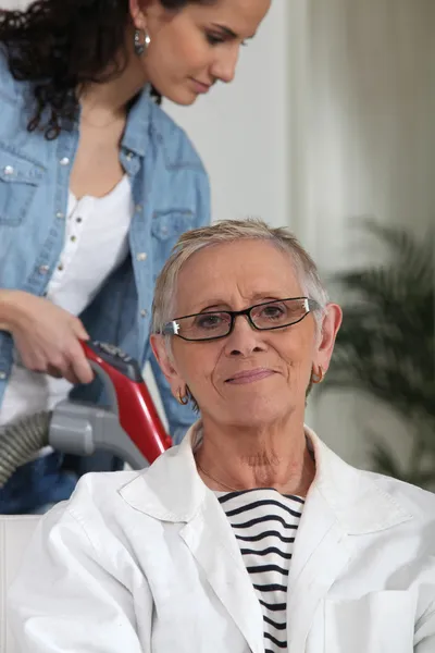 Junge Frau hilft einer älteren Dame bei der Hausarbeit — Stockfoto
