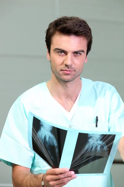 Γιατρό σε τρίβει κοιτάζοντας το xray ενός χεριού — Φωτογραφία Αρχείου