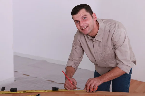 Tradesman marquant une mesure sur une planche de bois — Photo