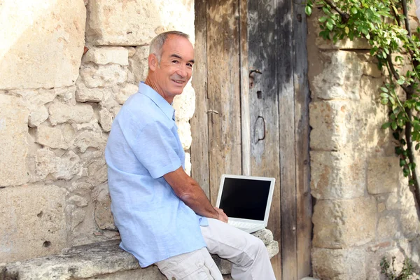 Senior man using a laptop with a blank screen — Stock Photo, Image
