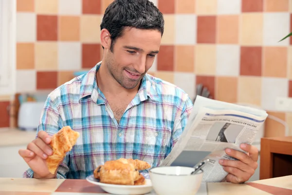 Człowiek czytanie gazety w czasie śniadania — Zdjęcie stockowe