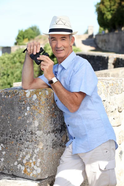 Senior man op een citadel met een paar van verrekijkers — Stockfoto