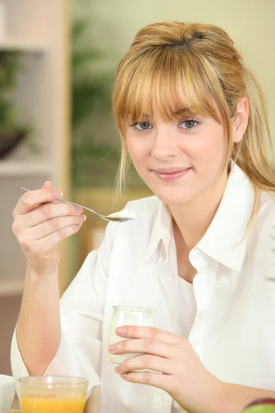 Молодая женщина ест йогурт за завтраком — стоковое фото