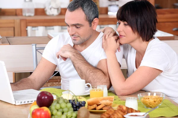 Couple with computer during breakfast — Stock Photo, Image