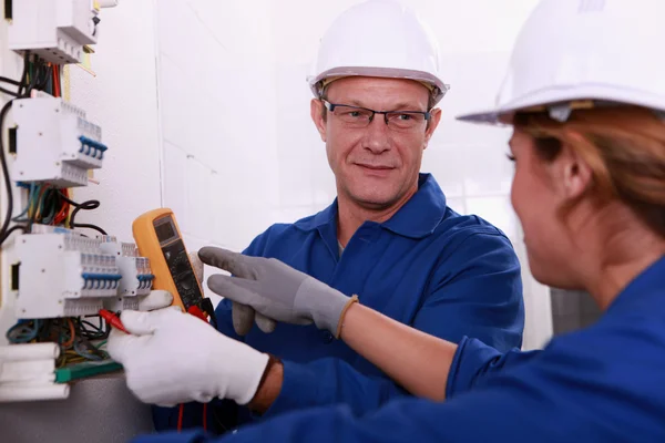 Elektrikli bir metre üzerinde çalışan elektrikçiler — Stok fotoğraf