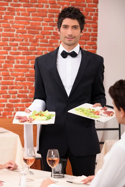 Официант доставляет еду к столу — стоковое фото