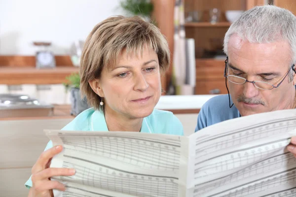 Pareja leyendo el periódico en la cocina —  Fotos de Stock