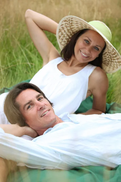 40 let starý muž a žena, uvolňující a lehnout si na louce — Stock fotografie