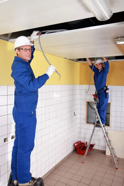 Zwei Elektriker arbeiten an der Decke — Stockfoto