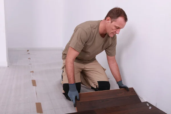 Uomo posa di un pavimento in legno — Foto Stock