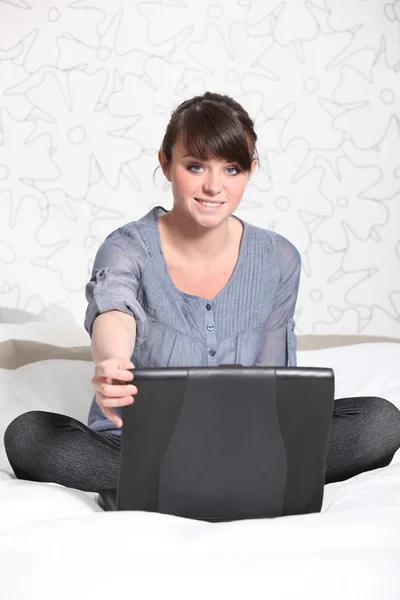 Ung kvinna avkopplande framför en bärbar dator — Stockfoto