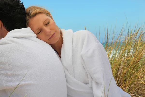 Couple sat in bathrobes at the sea — Stock Photo, Image