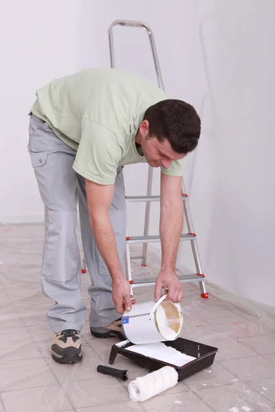 Decorator pouring paint into a tray — Stock Photo, Image