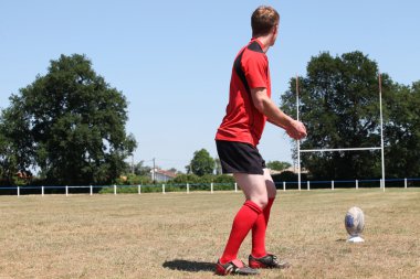 A rugbyman practicing his kick. clipart