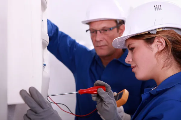 Een jonge vrouw die werkt op een elektriciteitsmeter vergezeld met een 45 jaar o — Stockfoto