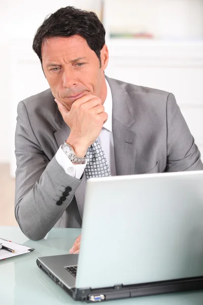 Affärsman förvirrad av sin laptop — Stockfoto