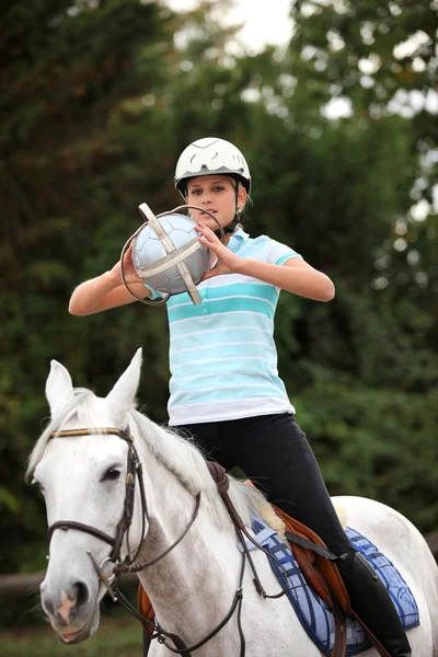 Молодая женщина играет в лошадиный мяч — стоковое фото