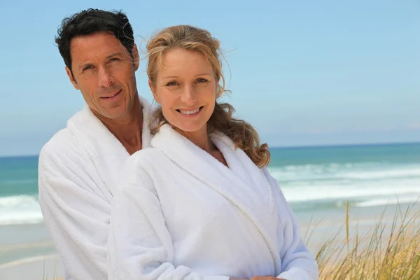 Couple in robes on the beach — Stock Photo, Image