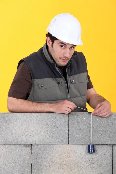 Bricklayer with a plumb line — Stock Photo, Image