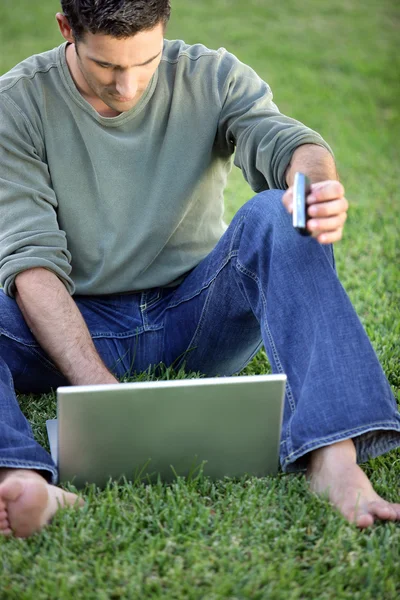 Mannen satt barfota i arkiverat med laptop — Stockfoto