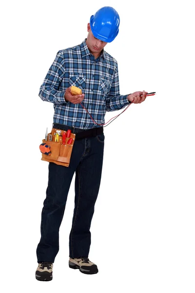 Um eletricista masculino verificando um voltímetro . — Fotografia de Stock
