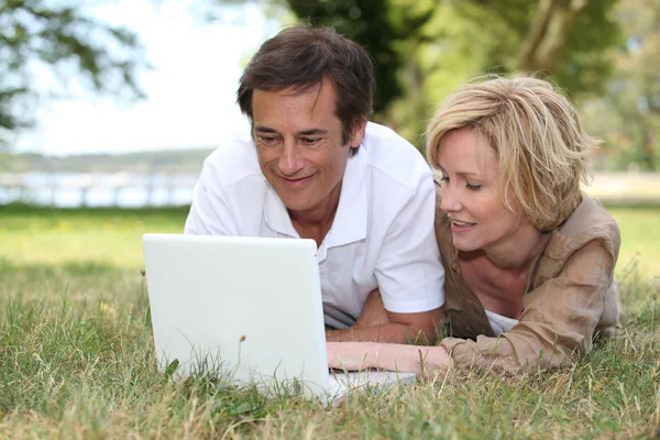 Paar blickt im Park auf seinen Laptop — Stockfoto
