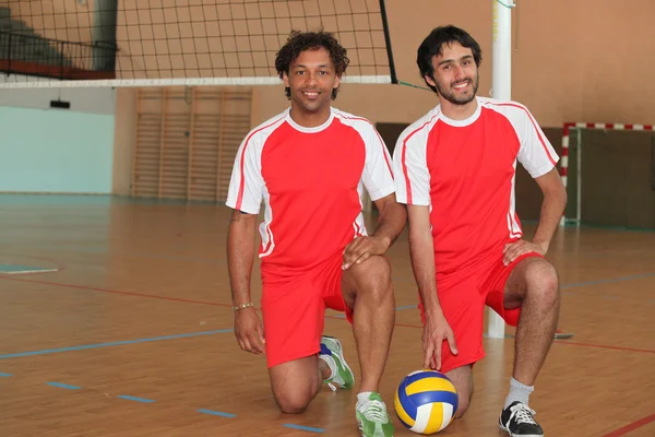 Dos jugadores de voleibol arrodillados con pelota en pista cubierta —  Fotos de Stock