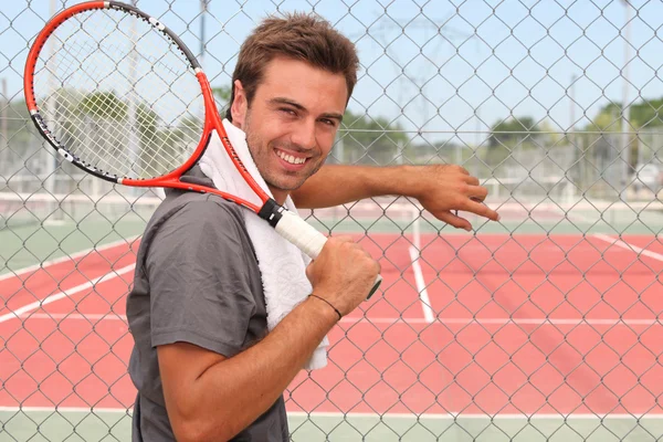 El hombre se paró frente a la cancha de tenis sosteniendo raqueta sobre el hombro — Foto de Stock