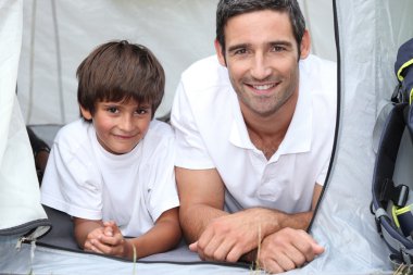 Father and son camping in a tent clipart