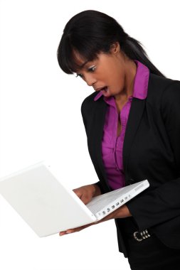 Afro-American businesswoman holding her laptop and looking very surprised clipart