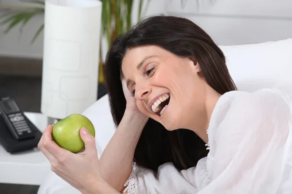 Woman laughing at an apple — Stock Photo, Image