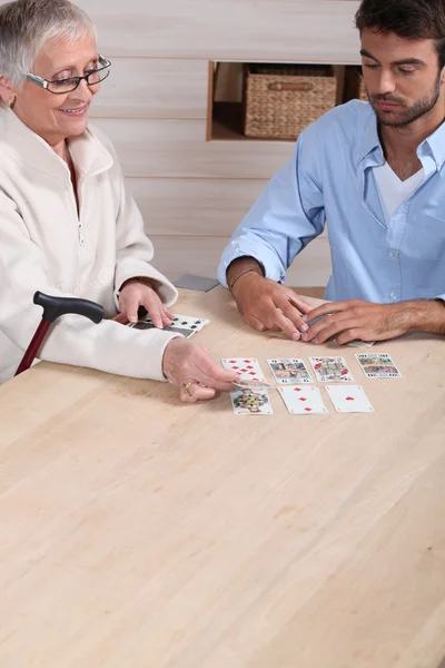 Old woman playing cards with young man — Stock Photo, Image