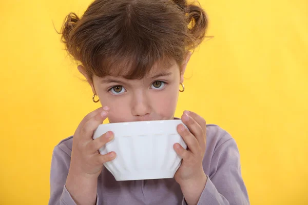 Lilla flickan dricka ur skål — Stockfoto