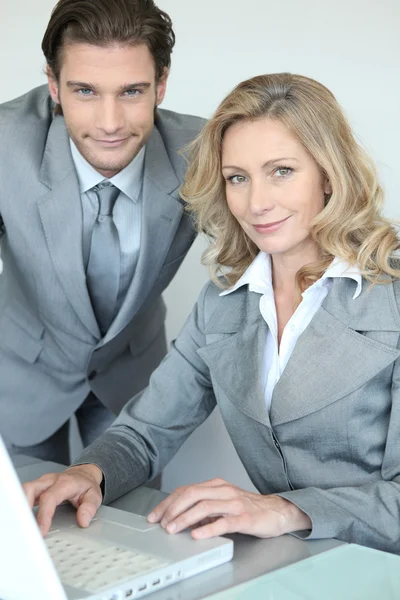 Um homem de negócios e uma mulher de negócios trabalhando na frente de um laptop e olhando — Fotografia de Stock