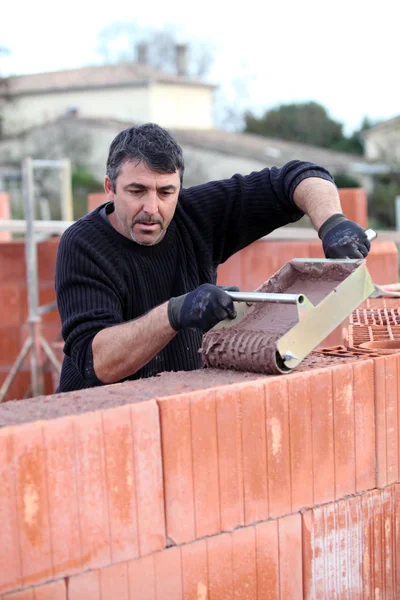 Mann schüttet nassen Zement an Wand — Stockfoto