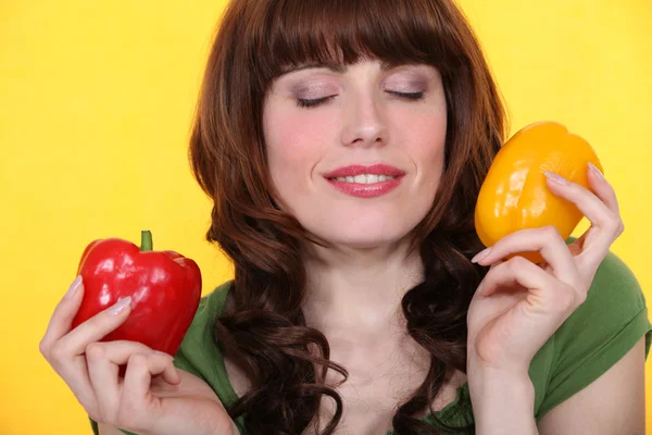 Woman with eyes closed holding peppers — Stock Photo, Image