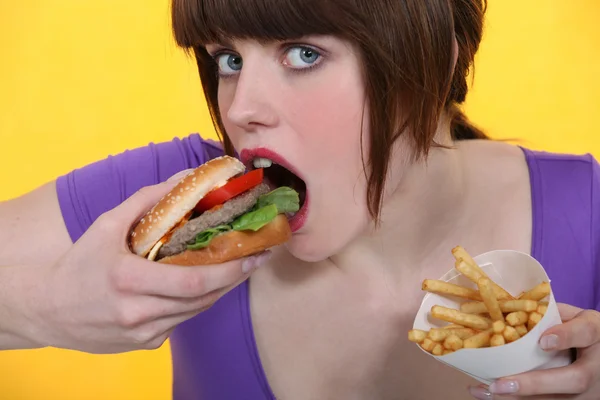 Nő eszik hamburgert és a sült krumpli — Stock Fotó