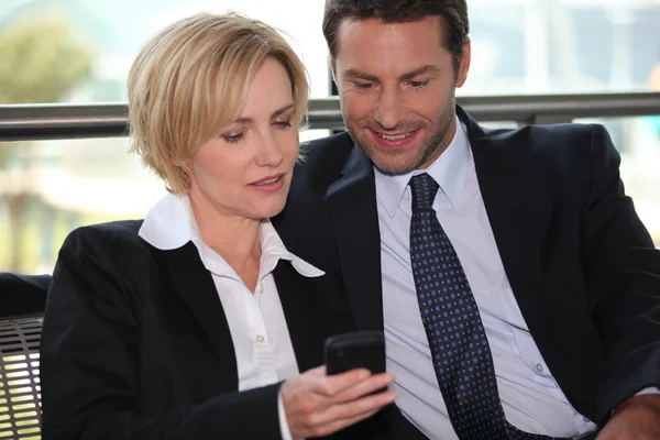 Geschäftsmann und Frau schauen aufs Telefon — Stockfoto