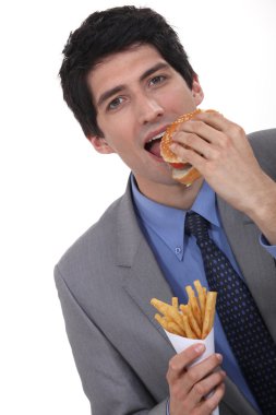 Businessman eating burger and fries clipart