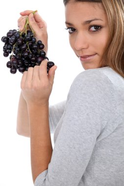 A young woman savouring sensually a grape clipart