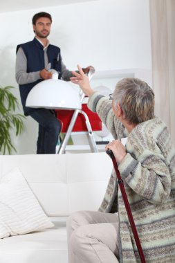 Young man putting up a light for an elderly woman clipart